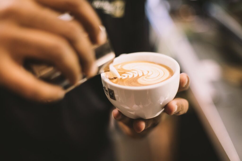 Person Holding White Ceramic Mug Filled With Cappuccino